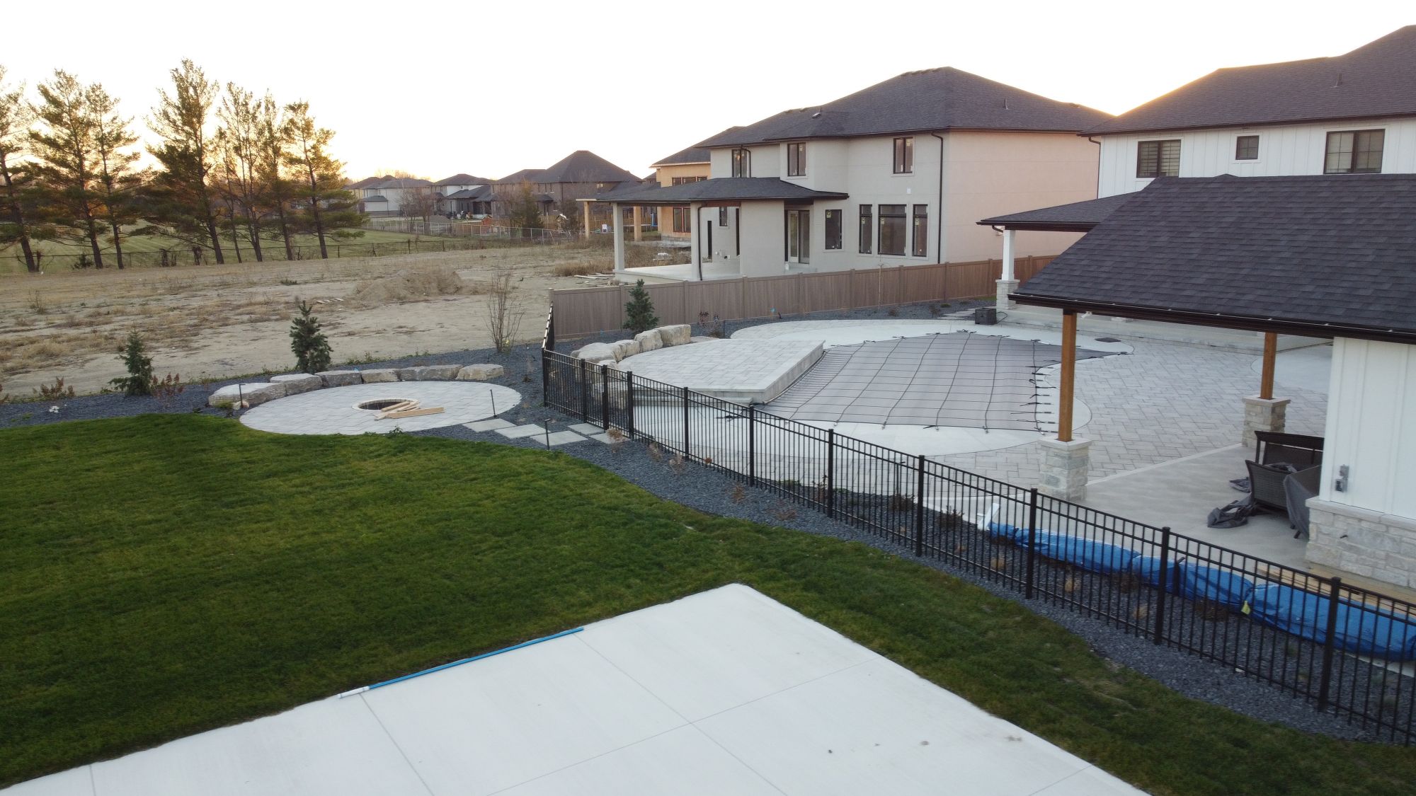 Working with North42 Landscaping (unfortunately now defunct) and Bluewater pools to build this hardscaped entertaining area - we ran Homewood Green Teak down the sides of the property, then blended the aluminum fence line to the grade then curved prior to the fire pit area.